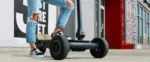 Person standing on CycleBoard Rover electric scooter in an urban street setting